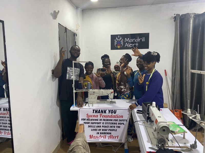 Deaf persons standing behind newly donated sewing machines