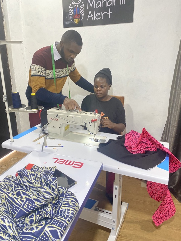Trainer demonstrating how to set stitches on a computerized industrial sewing machine